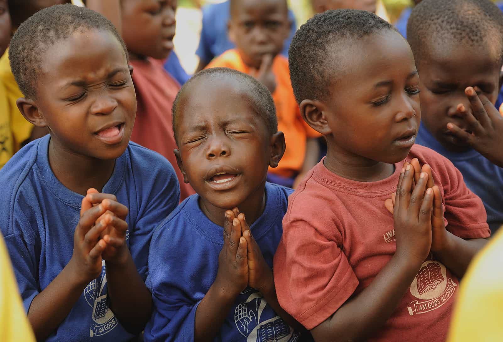 Three boys from Uganda fervently praying