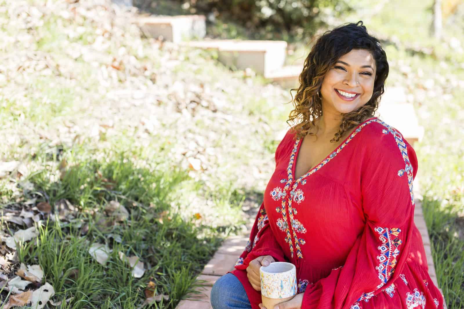 Aarti Sequeira sitting outside holding a mug