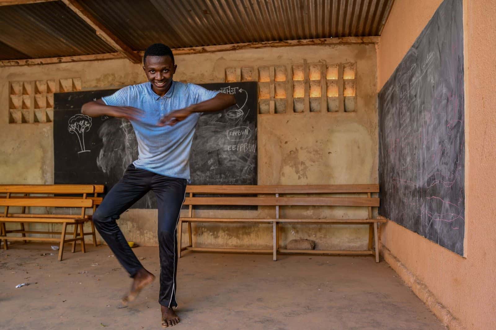 A young man dances in a classroom.