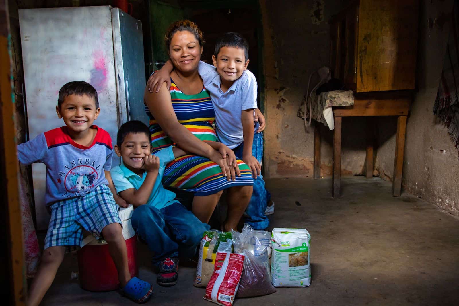 A woman and three boys sit in a home with food in front of them.