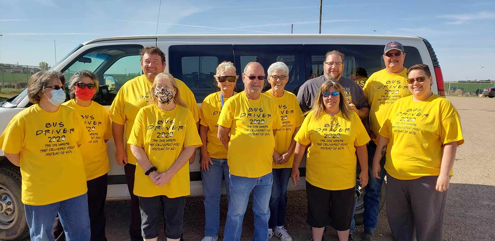 Bus drivers in front of a van wearing yellow shirts