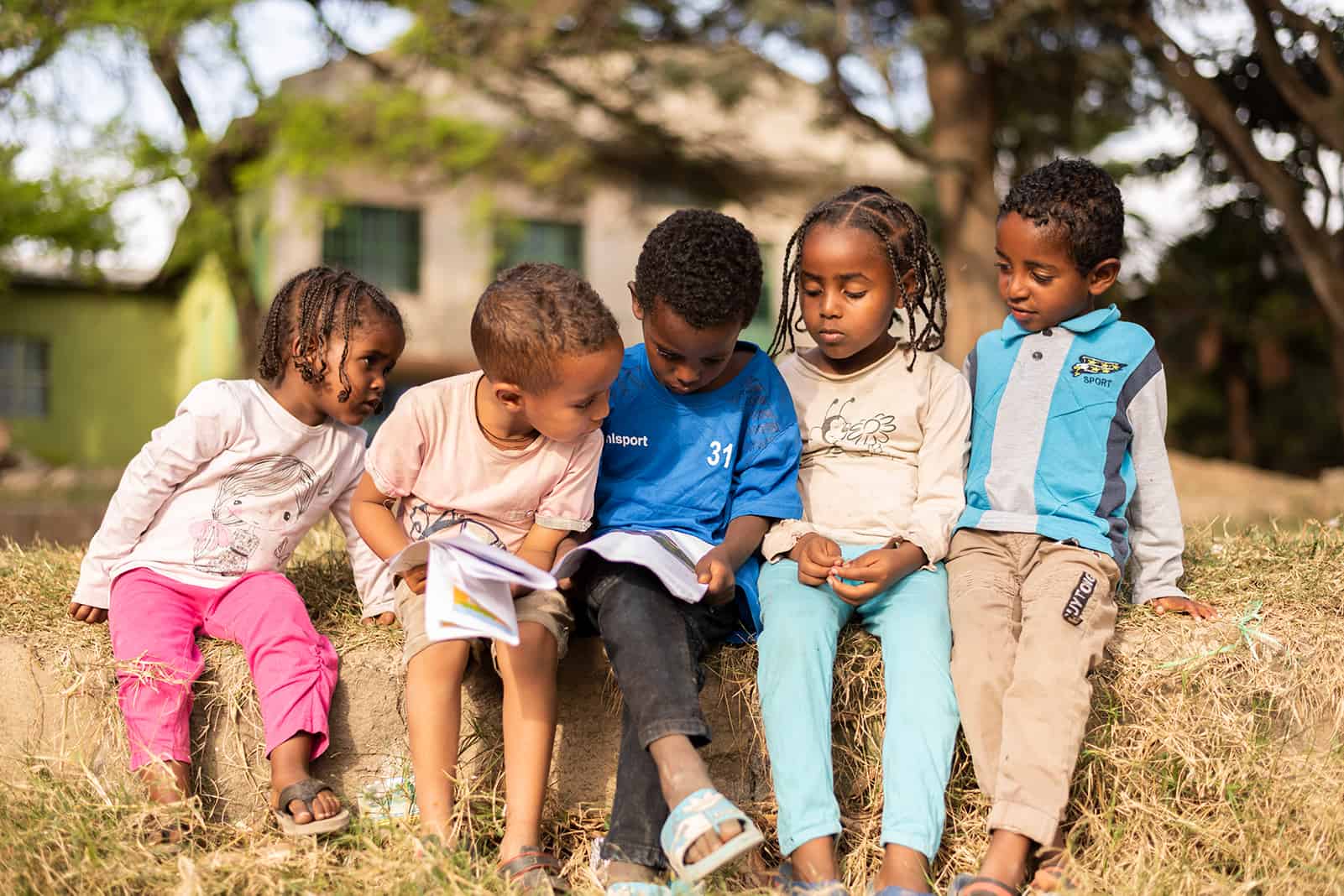 Children sitting on a wall reading letters