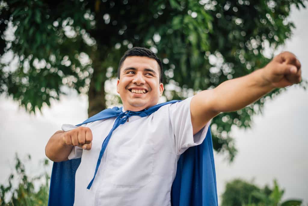 A man poses in a blue superhero cape