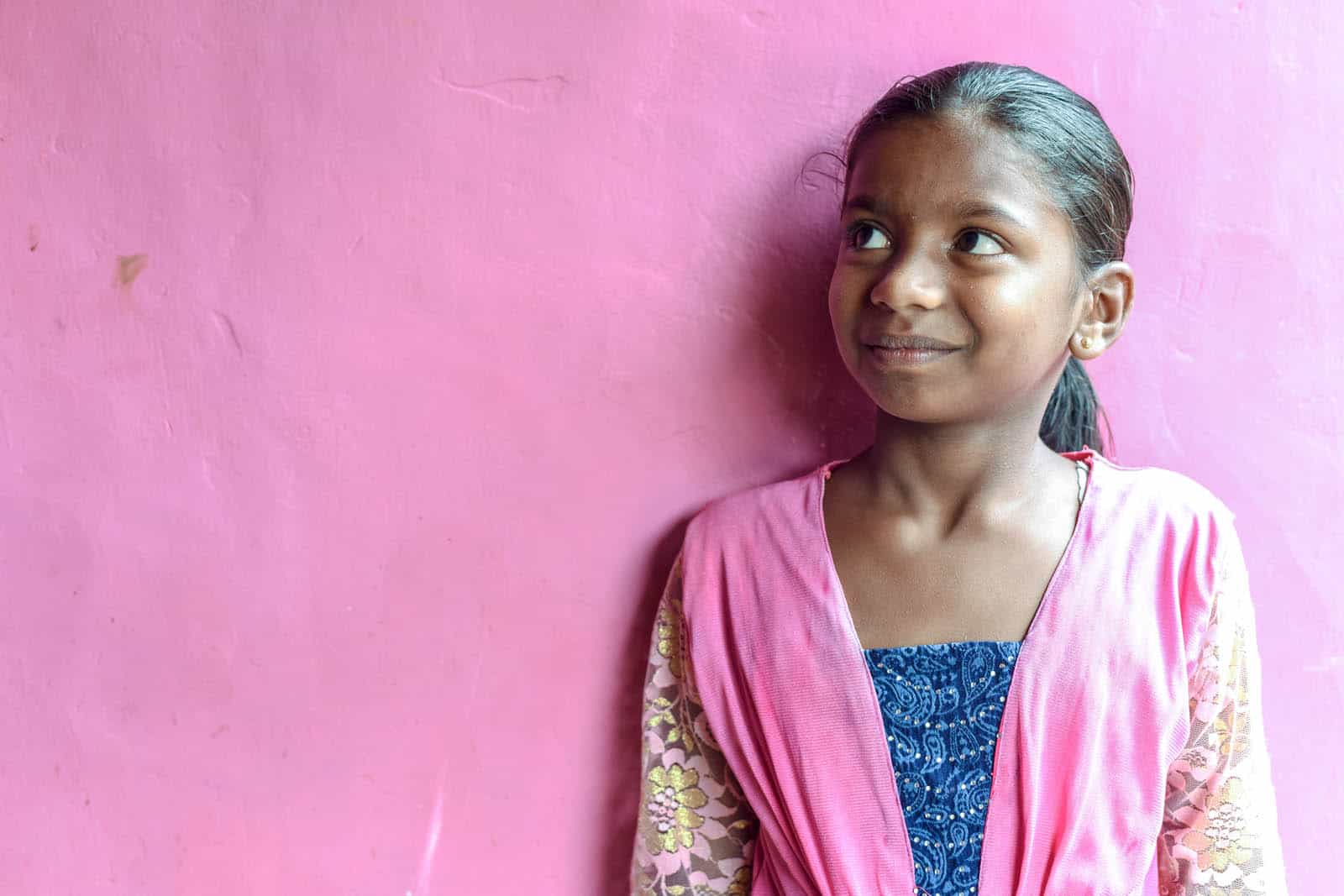 Rizwani stands in front of a pink wall