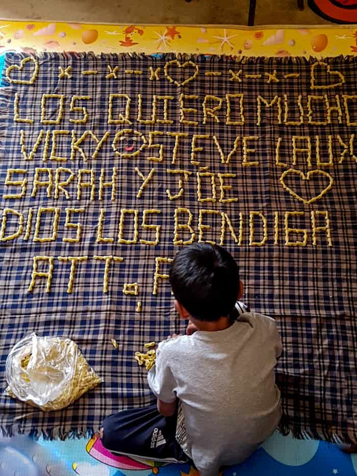 A boy makes words out of noodles