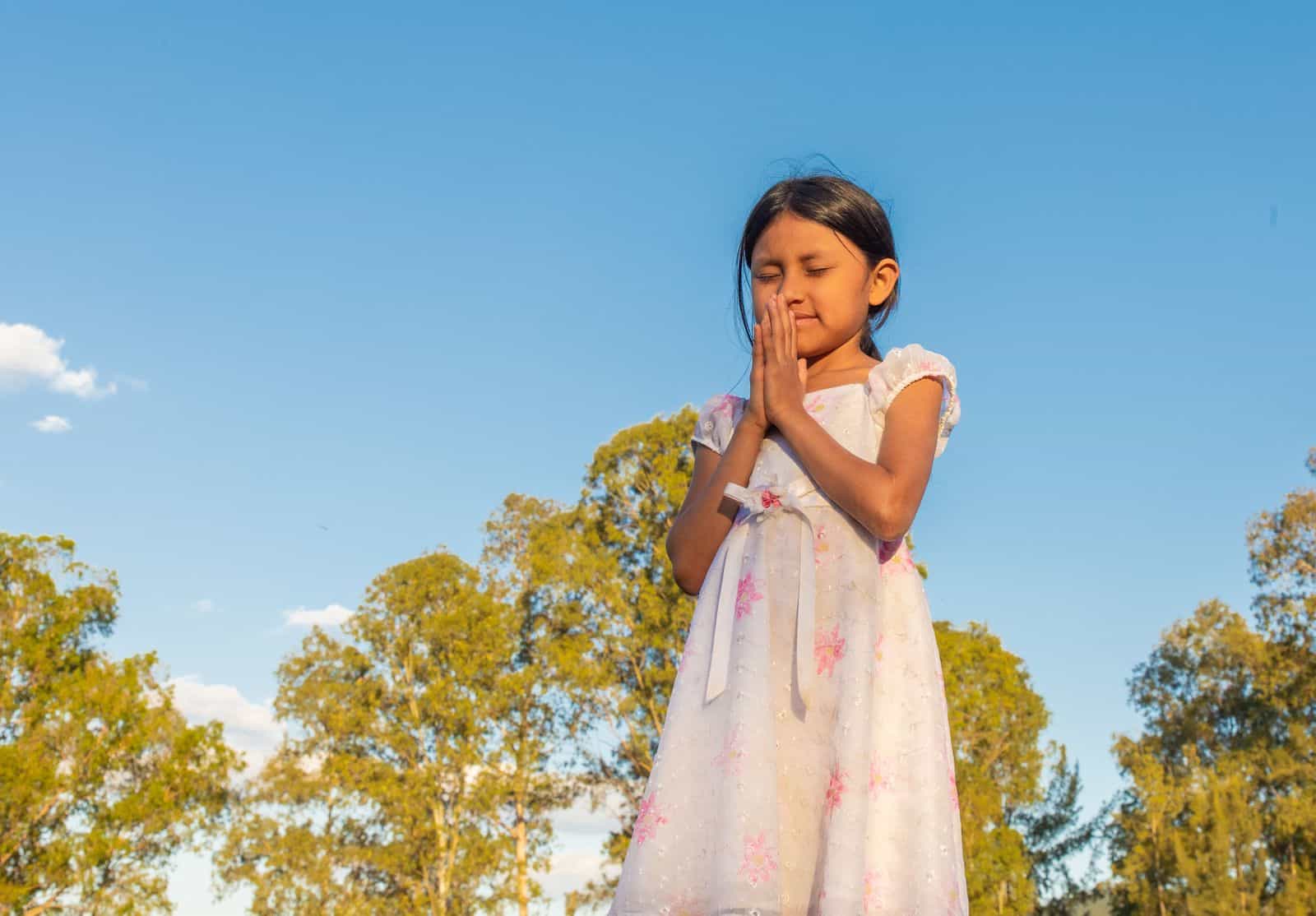 A girl prays, standing outside