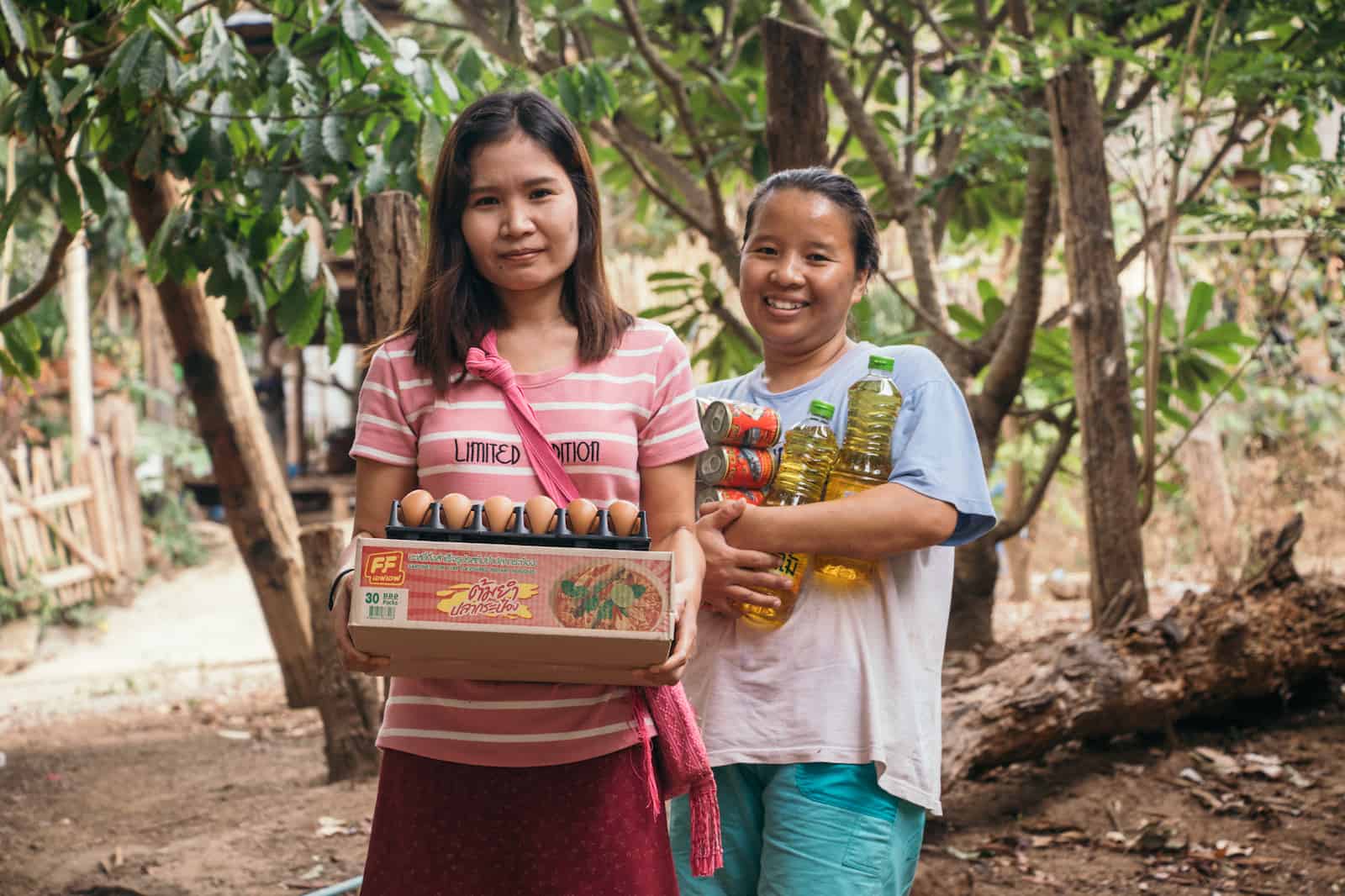 Two women holding an armful of food. 
