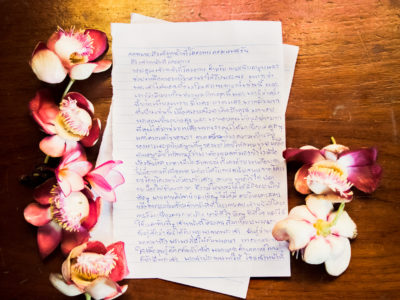 A letter written in Thai surrounded by flowers.