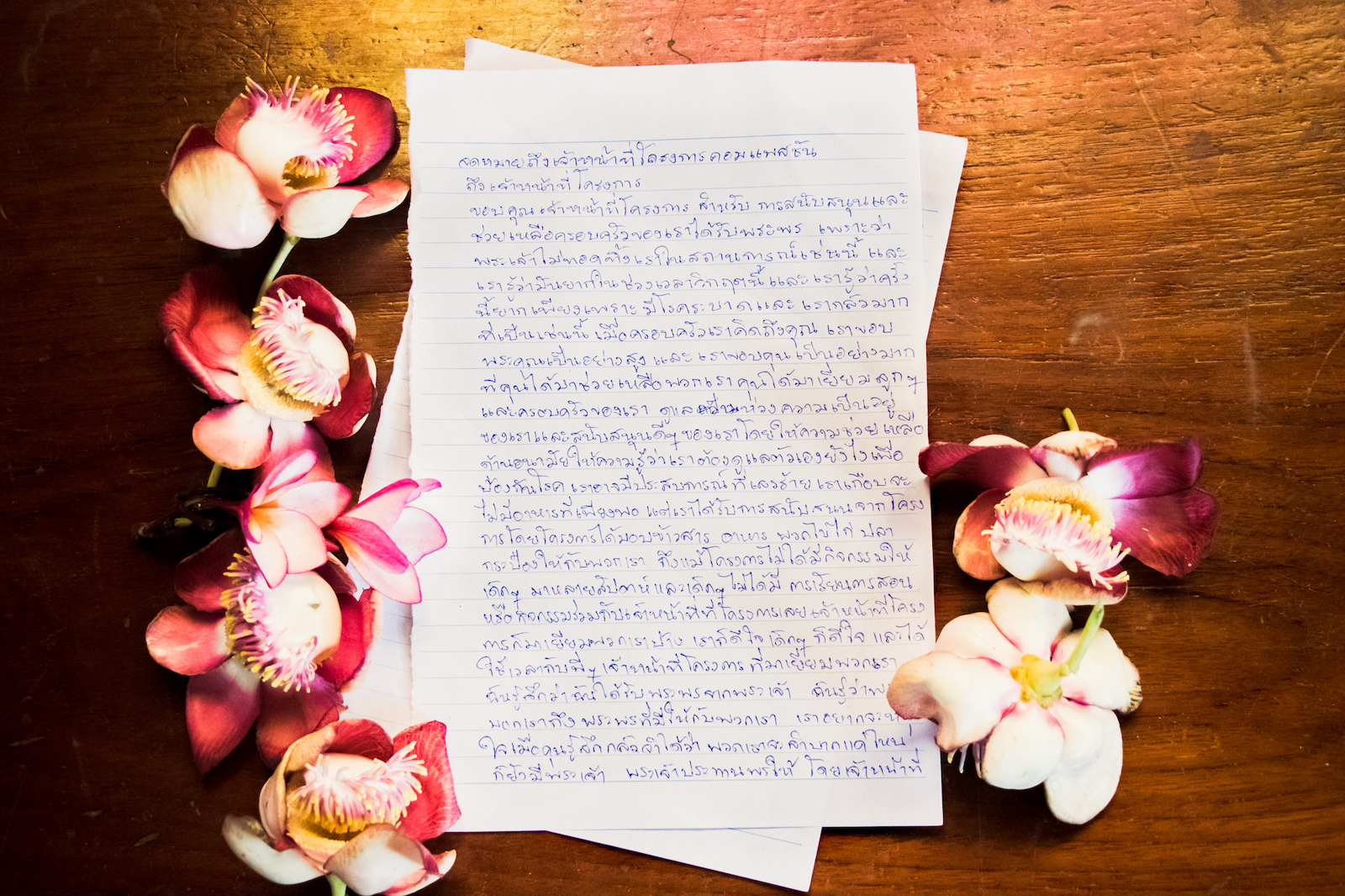 A letter written in Thai surrounded by flowers.