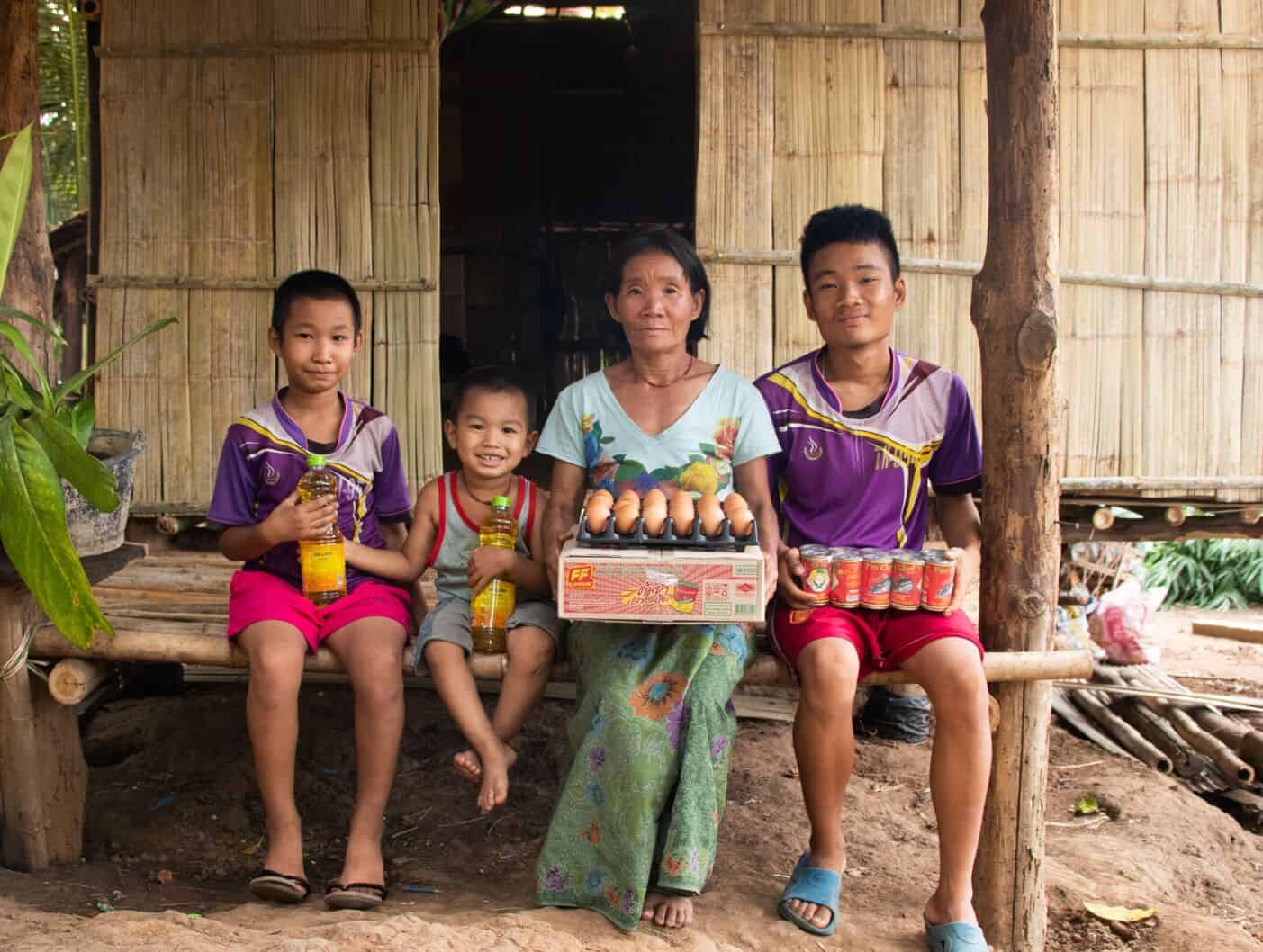 A woman and three children hold food in their laps.