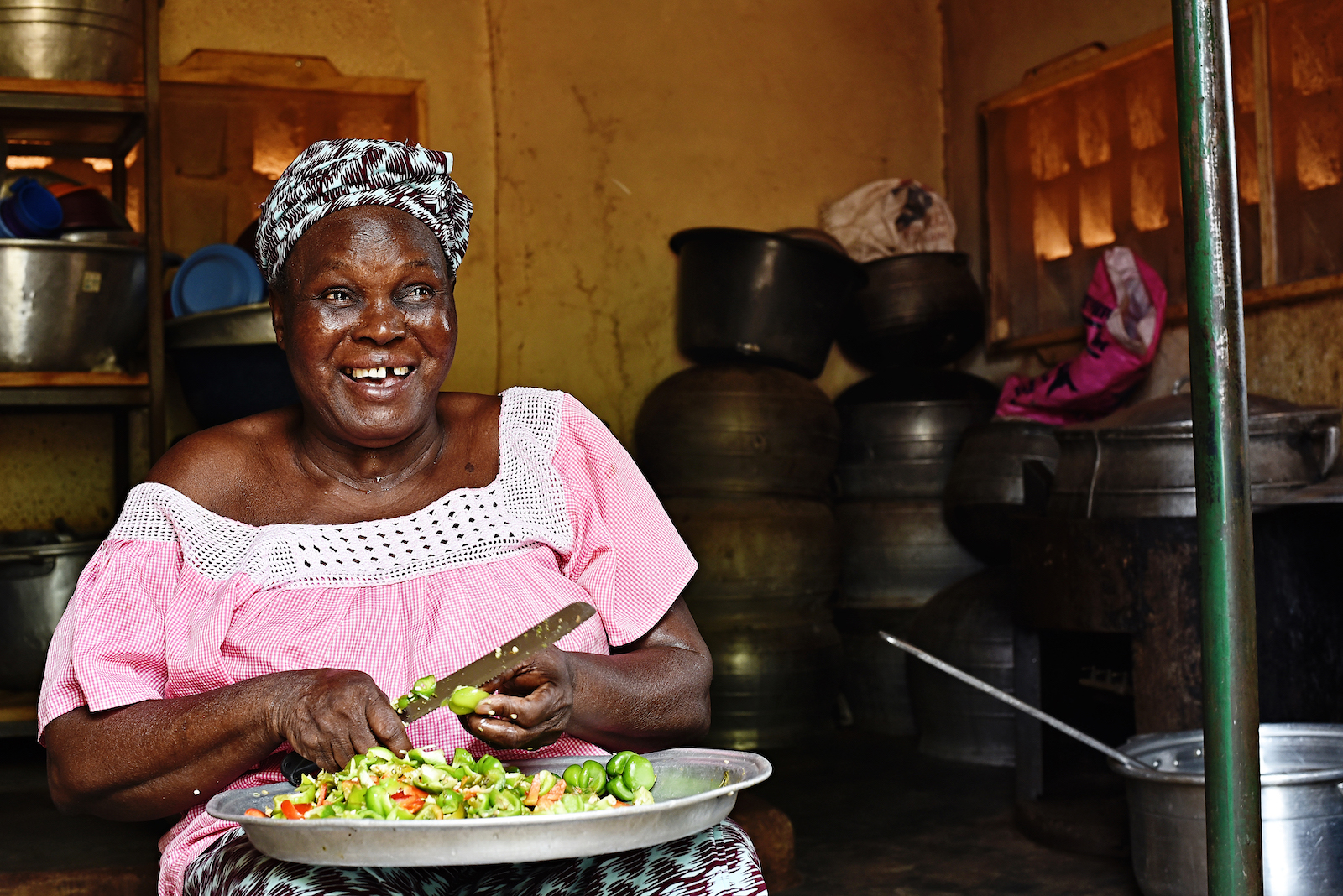 A woman sits in a kitchen cutting vegetables