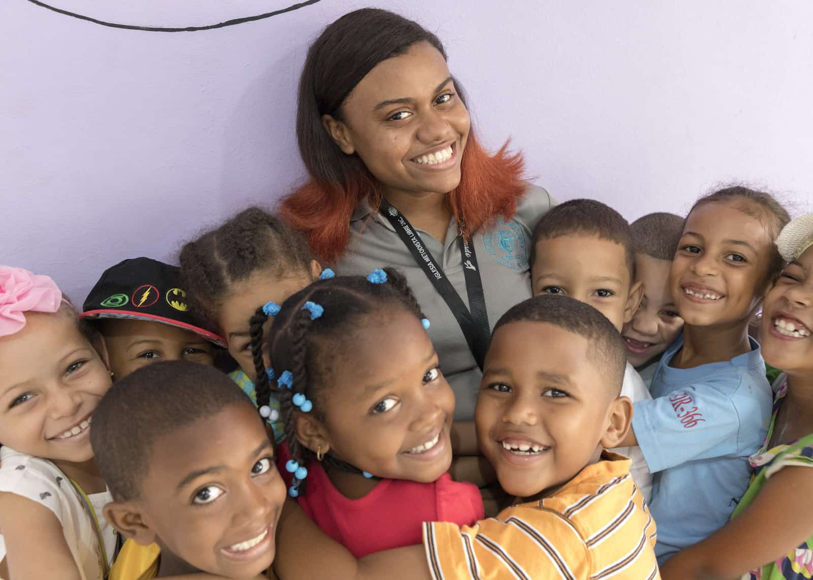 A woman stands with a group of children hugging her