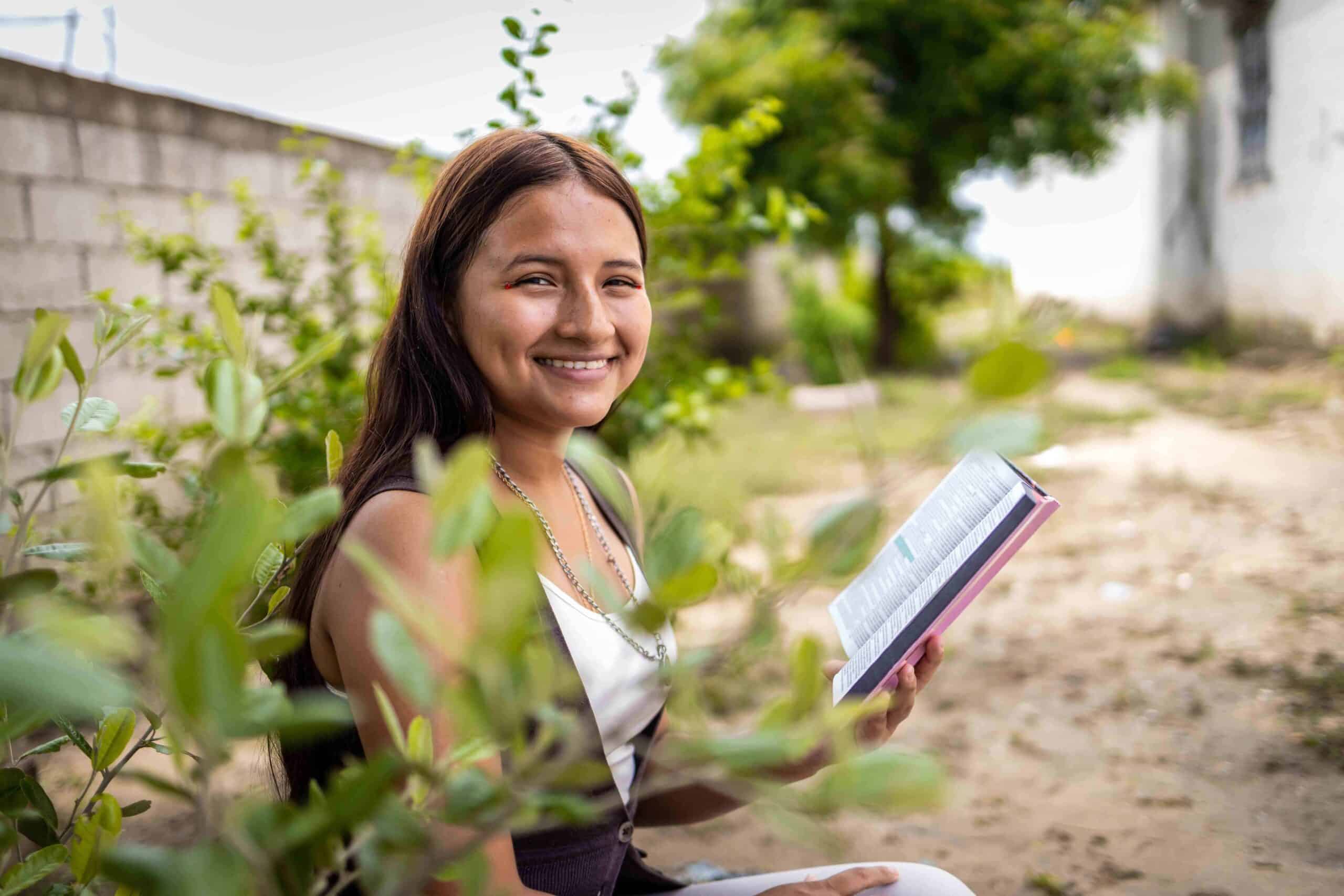 Young girl holds a Bible and smiles towards the camera
