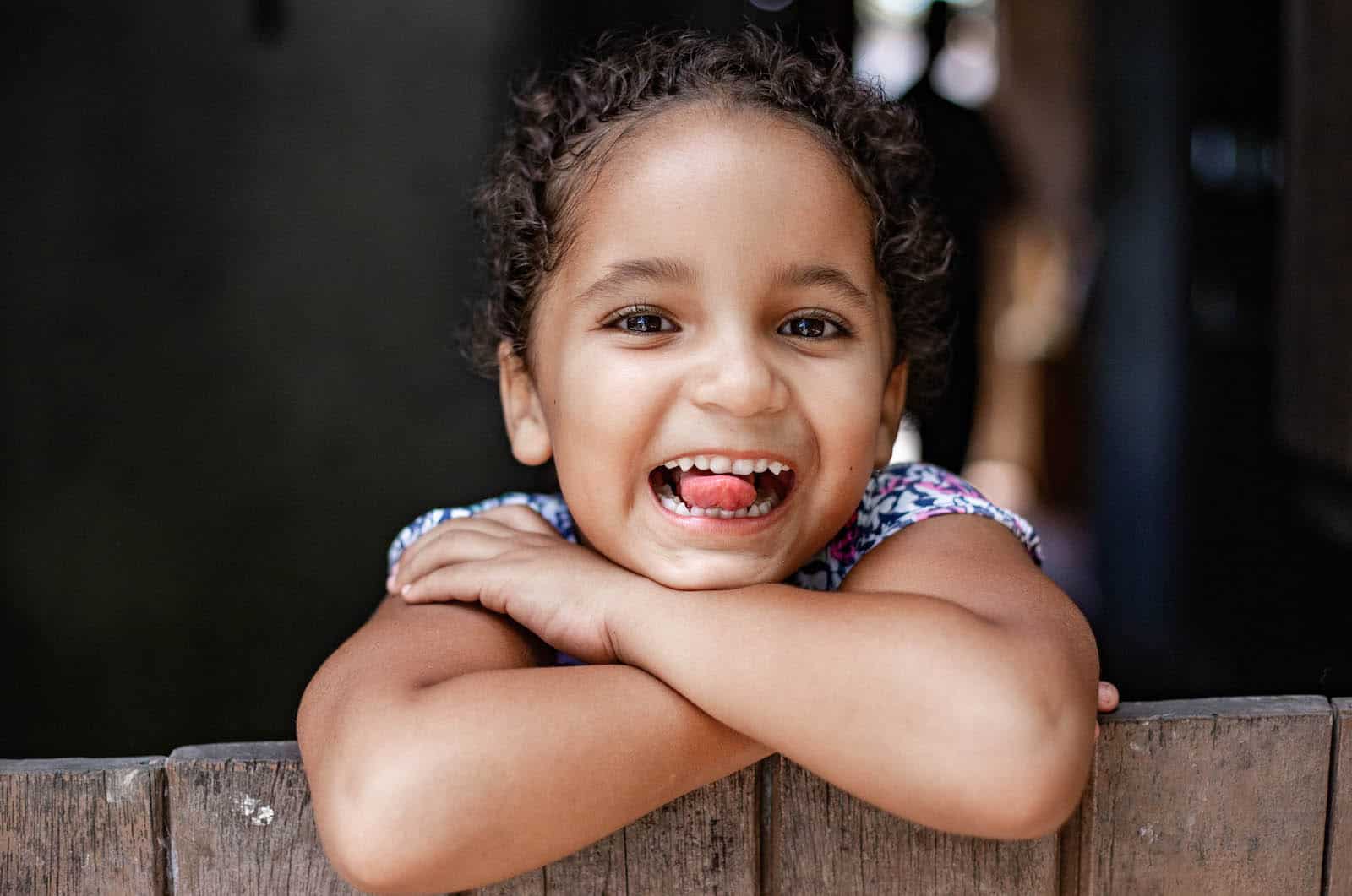 A girl smiles, sticking her tongue out at the camera