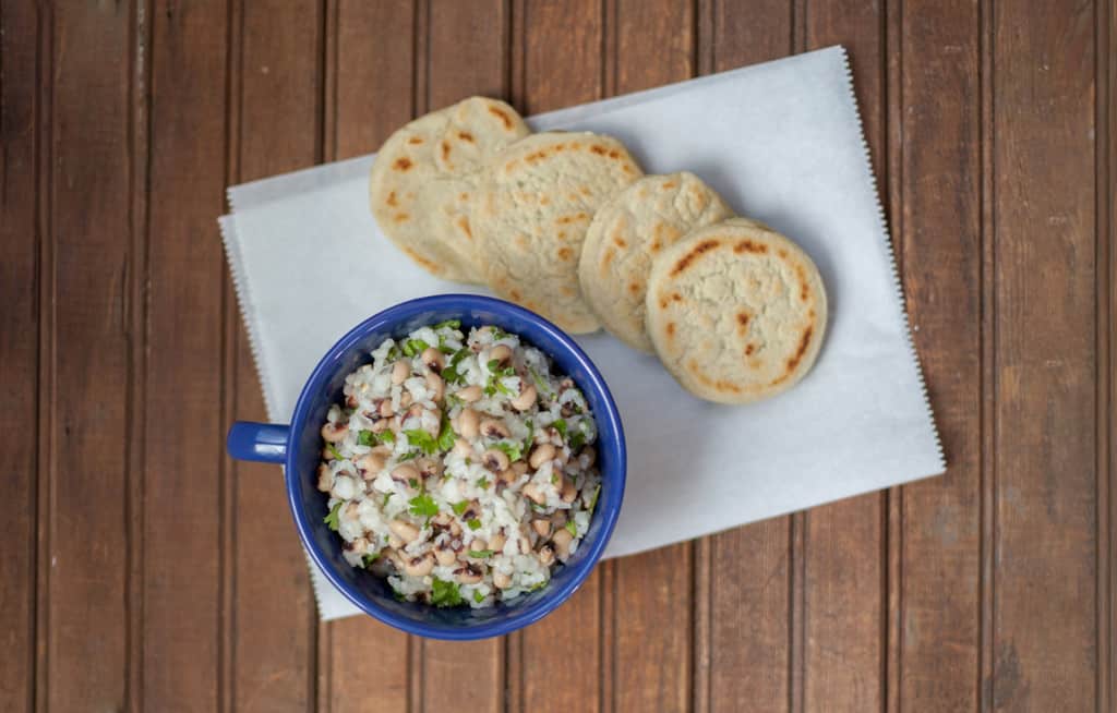 Baião de Dois in a blue bowl on a table with arepas.