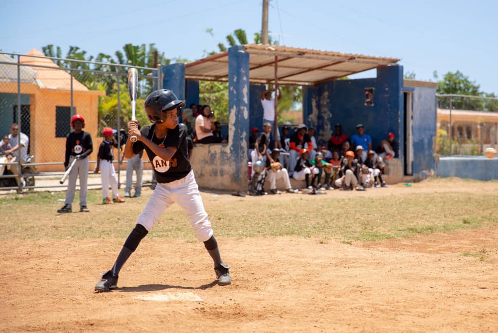 Boy holding a bat wearing a baseball uniform and helmet standing at homeplate waiting for a pitch.