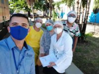 A man and four nurses wearing personal protective equipment look at the camera