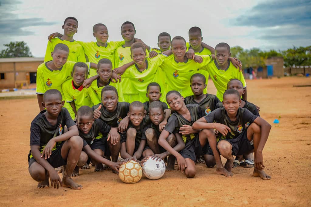  A group of boys posing with smiles and soccer balls.