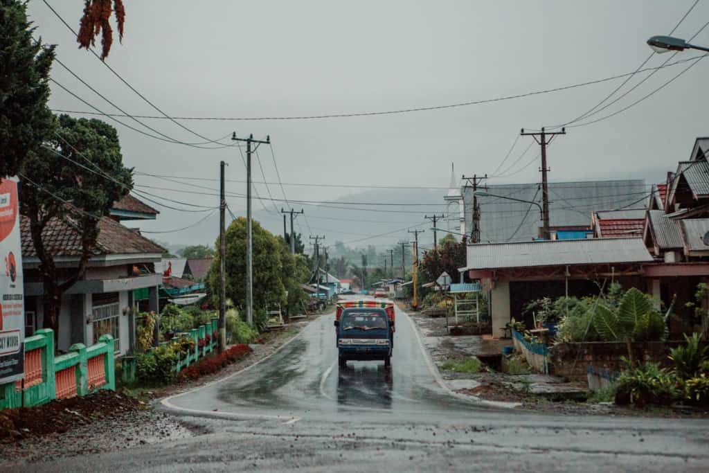 Truck driving on a wet street through a small town in Indonesia.