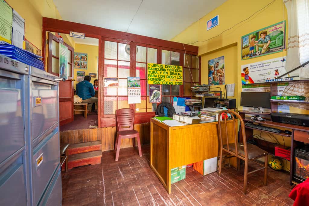 Inside an office with yellow walls at a Compassion center. There are filing cabinets and a desk.
