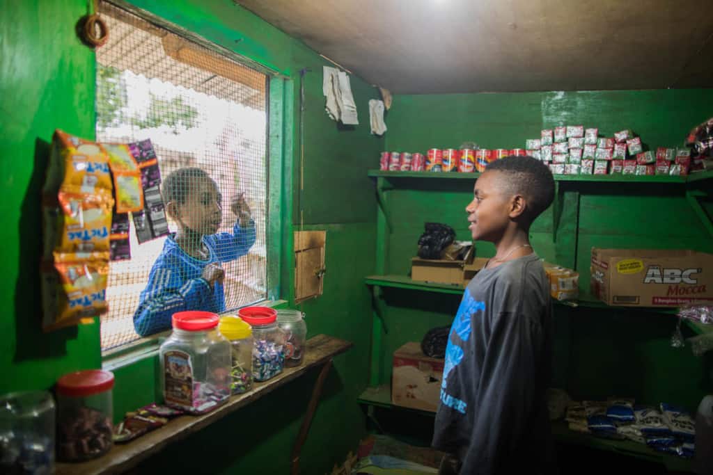 Petro is serving one of his customers who came to his green stall. The customers will usually order through the wire window. The items and change will be delivered through a small square hole.