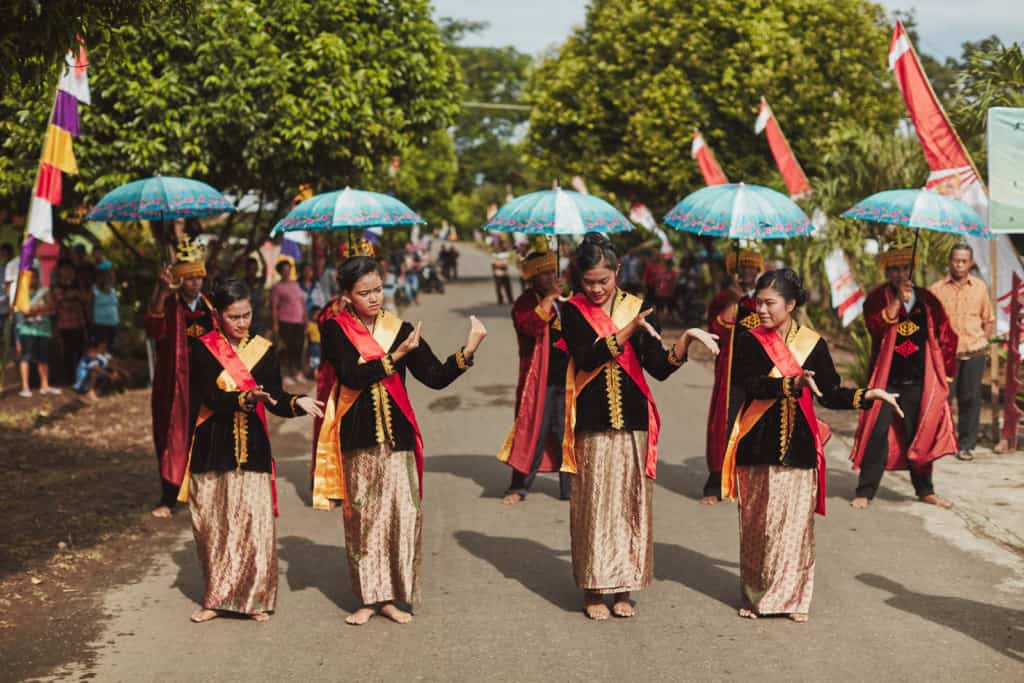 Teenage girls in costumes black shirts with gold and red sashes in the front of the parade to celebrate Christmas holiday.