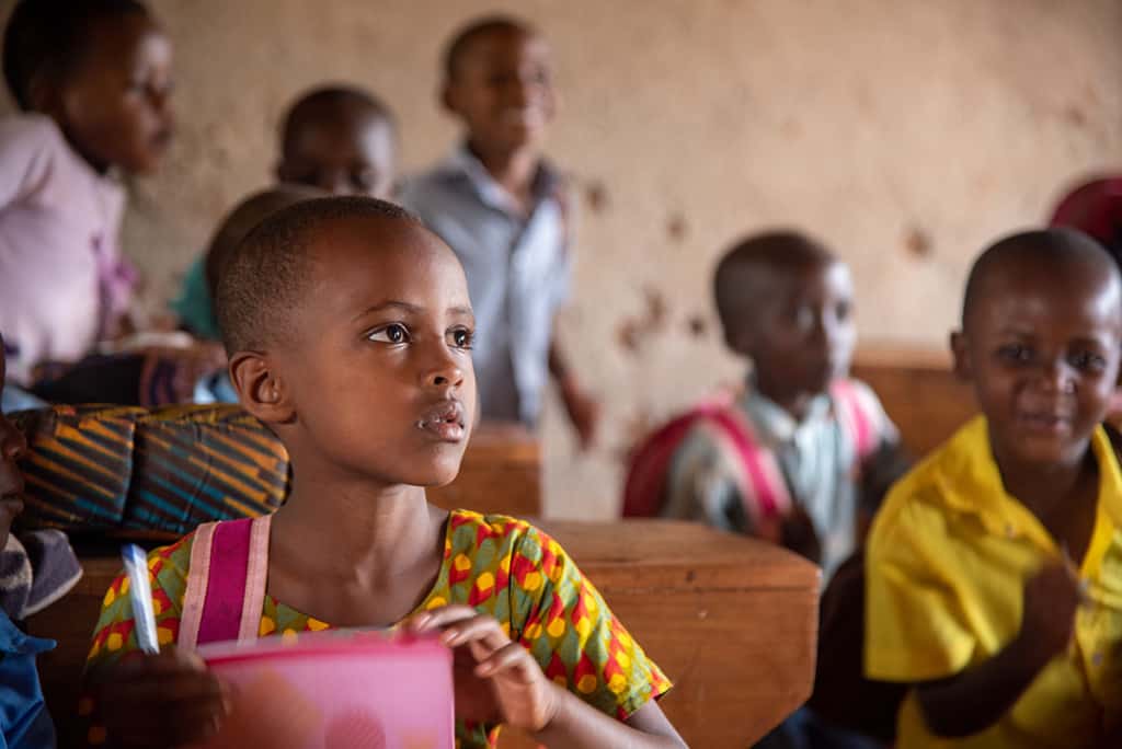 a girl in a classroom with other children has an attentive expression