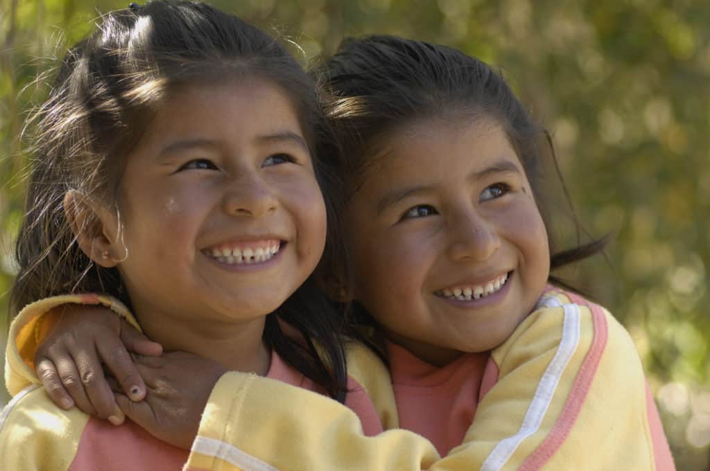 Two identical twin sisters in Bolivia hug each other and smile