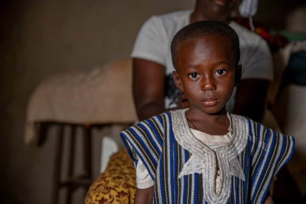 A child in Burkina Faso wearing a somber expression and traditional clothing