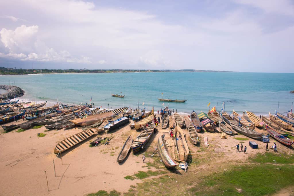 Many wooden boats on the shore of a large body of water