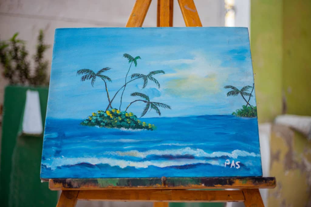 Jetmy's painting. The painting is of a blue sea and sky, with palm trees in the sea.