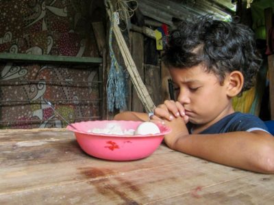A boy saying a prayer before eating