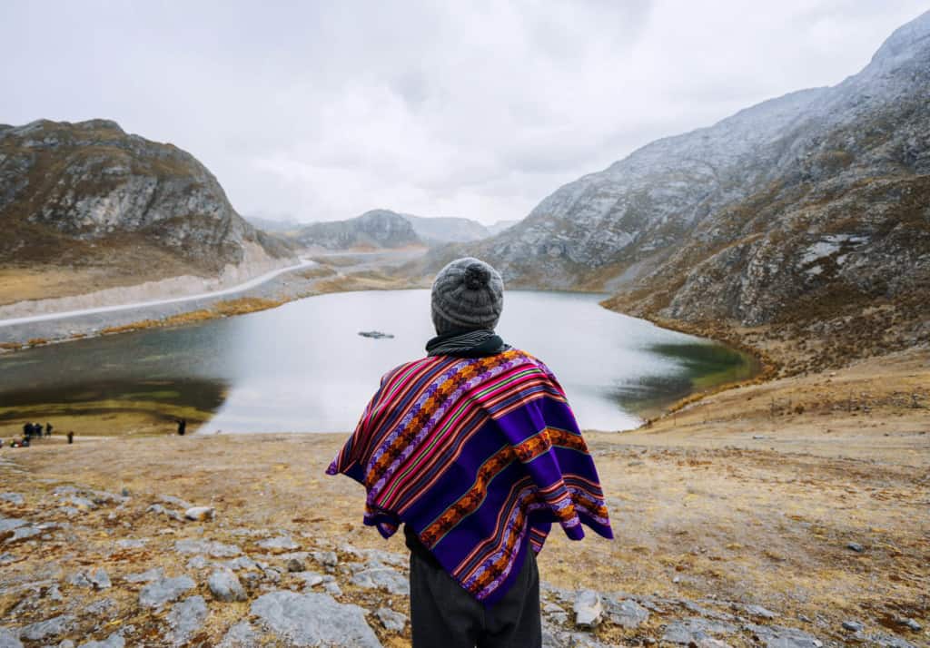 Person standing looking at lake in a mountain valley.