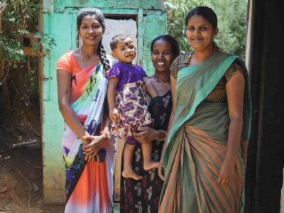 three women with a child in front of a colorful building