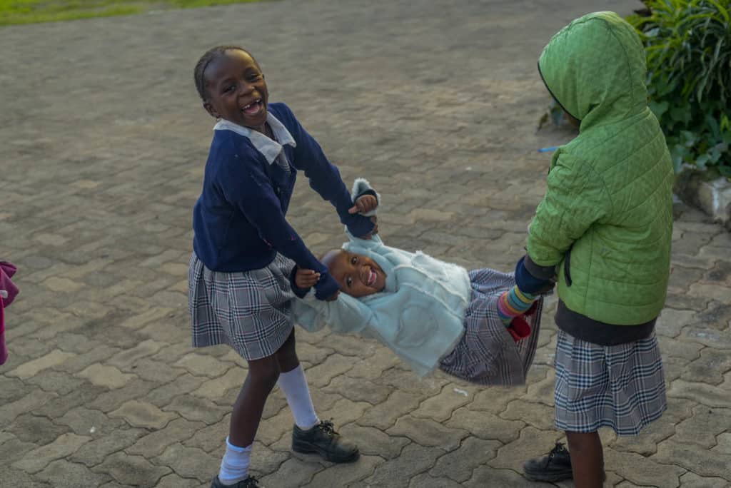 A group of beneficiary girls are playing together outside the Compassion center.