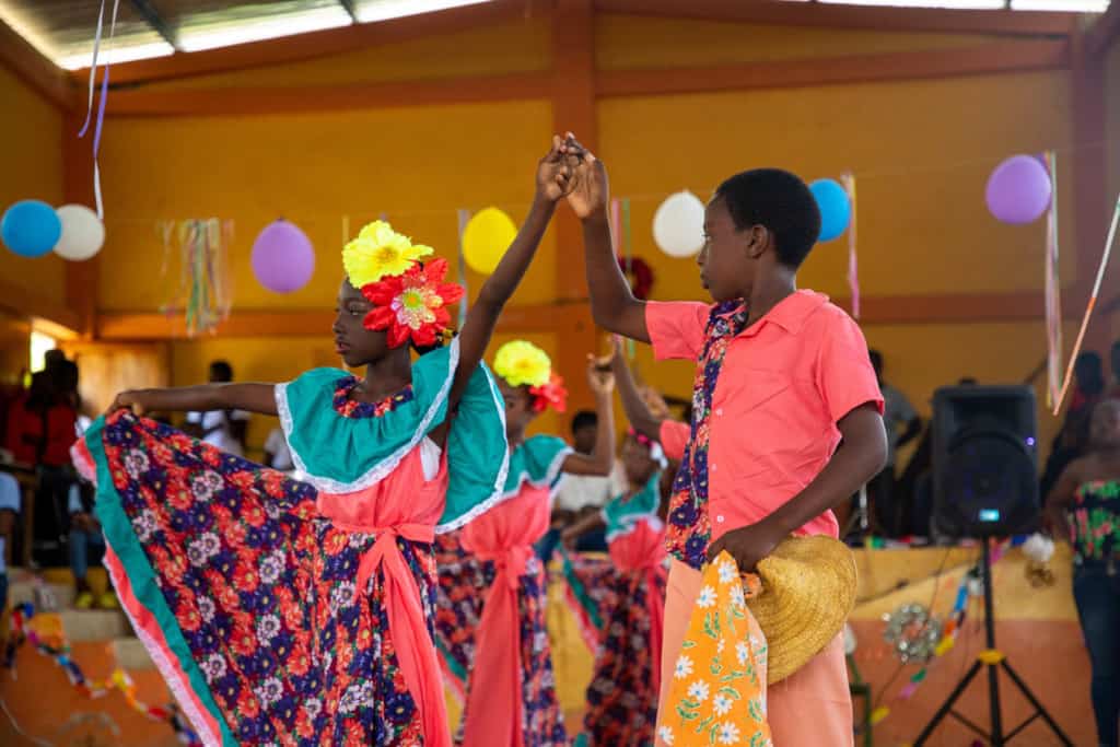 Students from the dance team in the gym, performing in the Christmas Show. They are wearing traditional outfits as they dance.