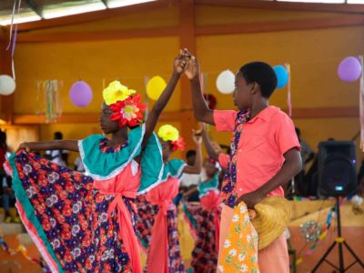 Students from the dance team in the gym, performing in the Christmas Show. They are wearing traditional outfits as they dance.