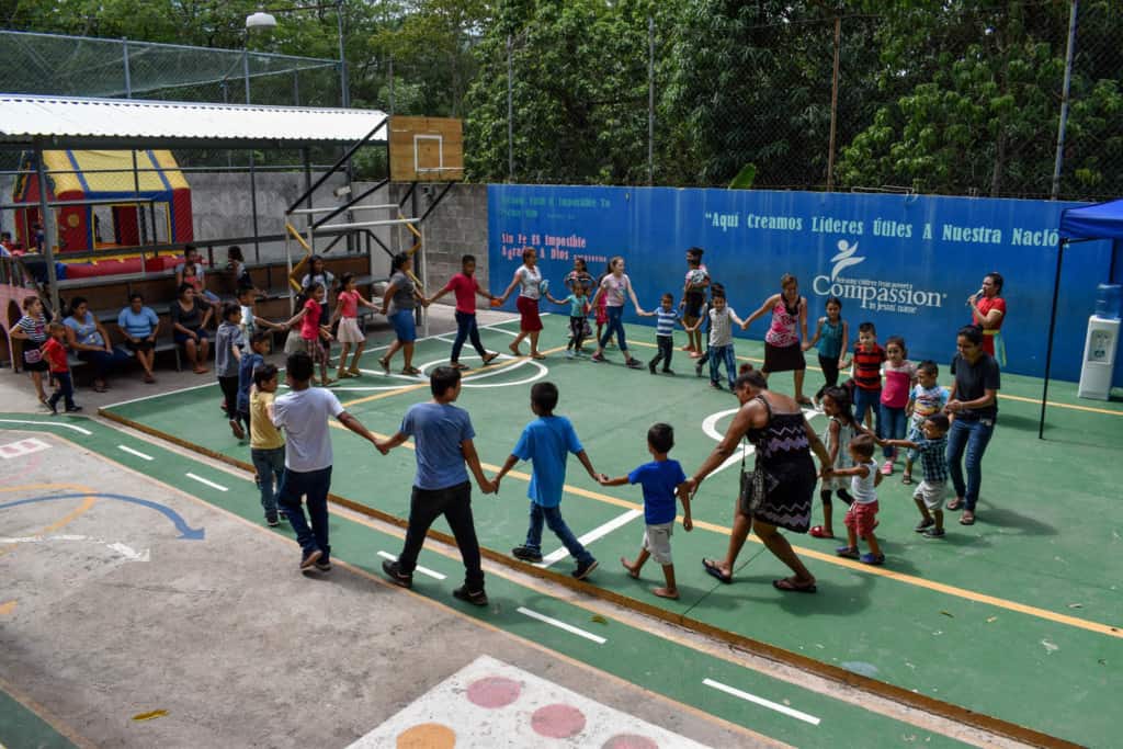 Children hold hands and walk in a circle as part of an activity.