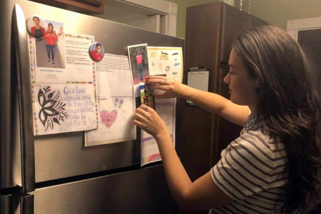Katie hangs a photo of her sponsored child on her refrigerator.