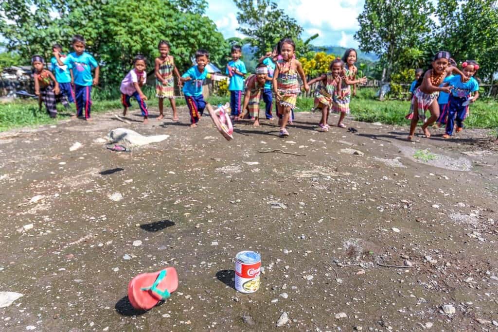 Children in Thailand throw flip-flops at a tin can, playing the game tumbang preso