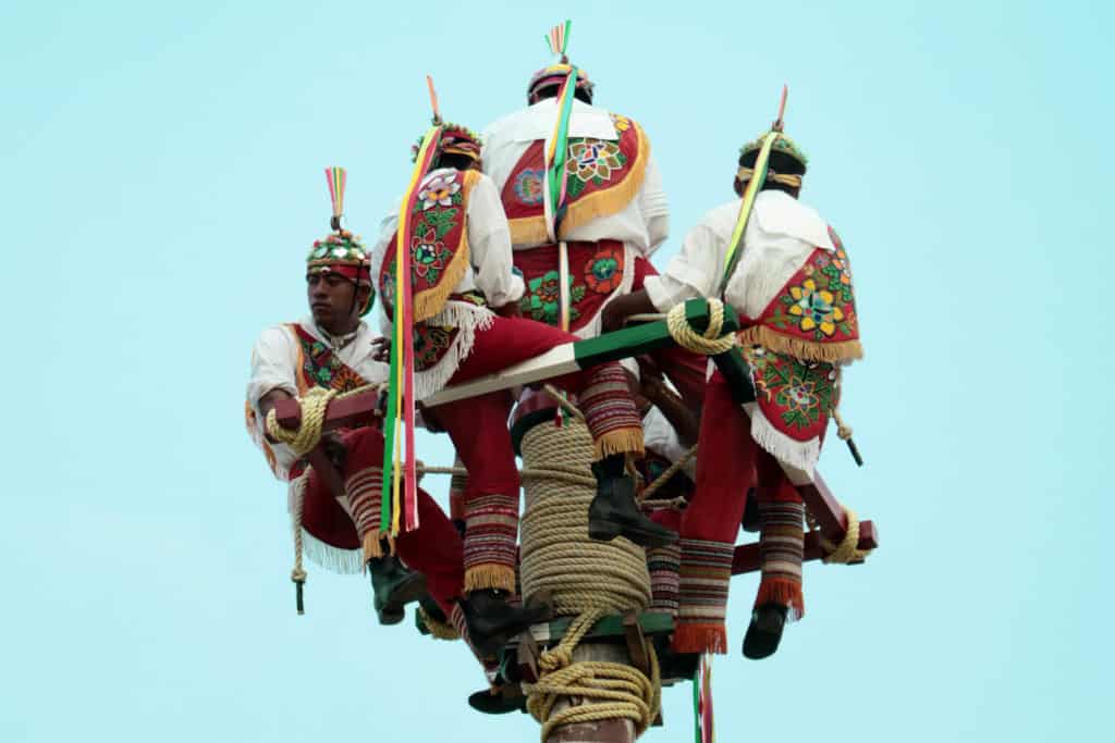 Men sitting on a pole in traditional dress