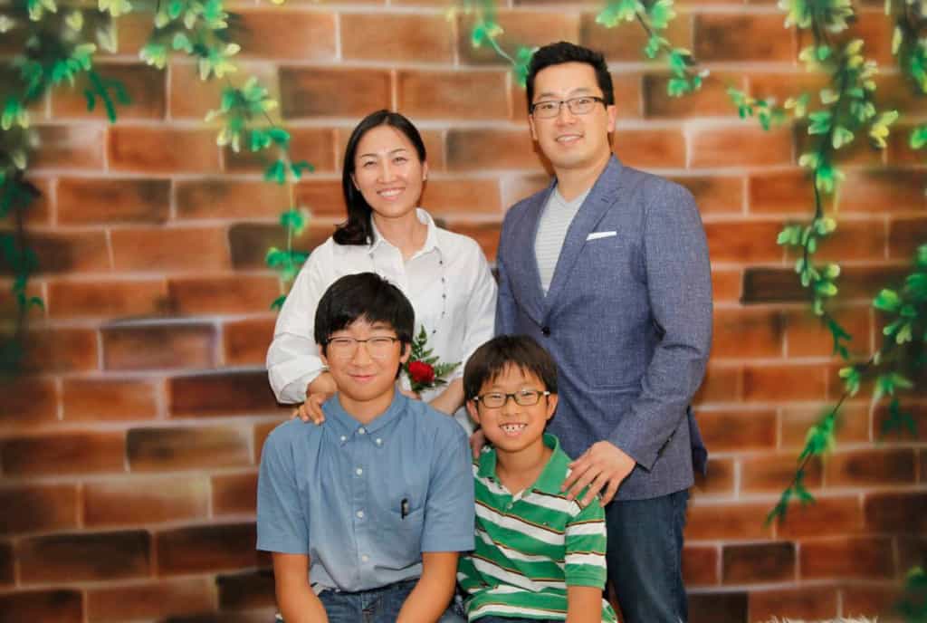 David Choi and his family posing in front of a painted wall.
