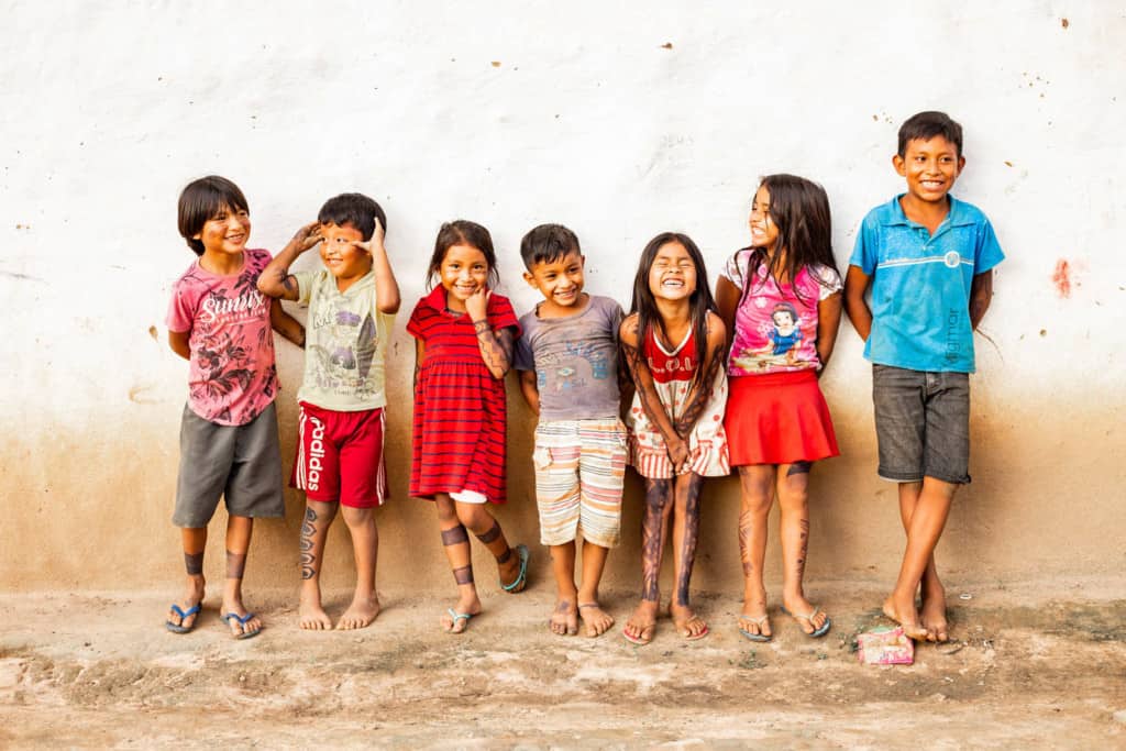 A group of children are standing against a wall in their neighborhood.