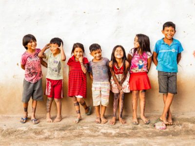 A group of children are standing against a wall in their neighborhood.