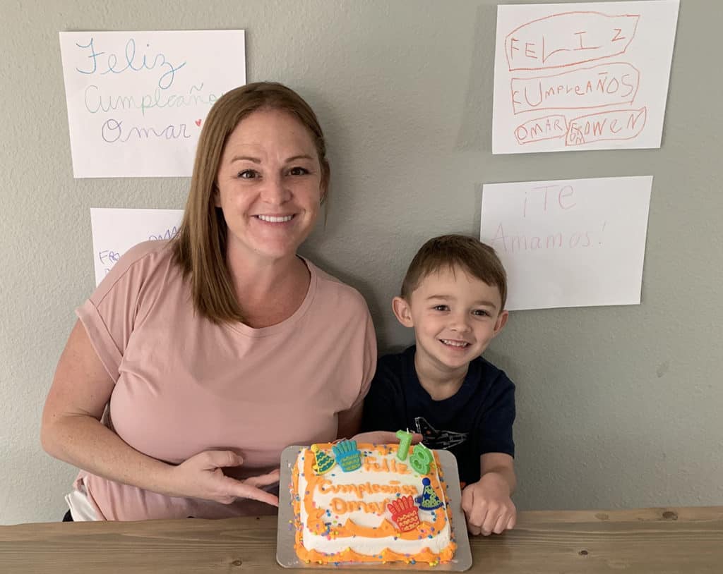 Kristen and her son Owen hold up a birthday cake made for one of their family's sponsored children, Omar.