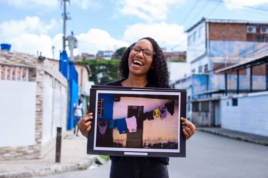 Rayane shows one of her favorite pictures. She is smiling at the camera as she holds up her picture.