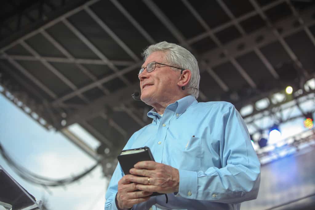 Luis Palau holds a Bible and closes his eyes to pray.