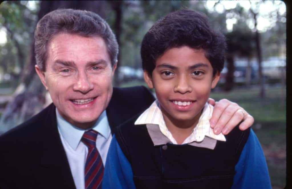 Luis Palau in a suit and tie puts his arm around his sponsored child, Fernando