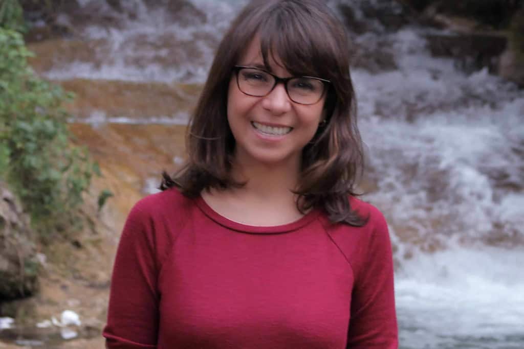 Lidia Beteta de Corado in a red shirt standing in front of a waterfall