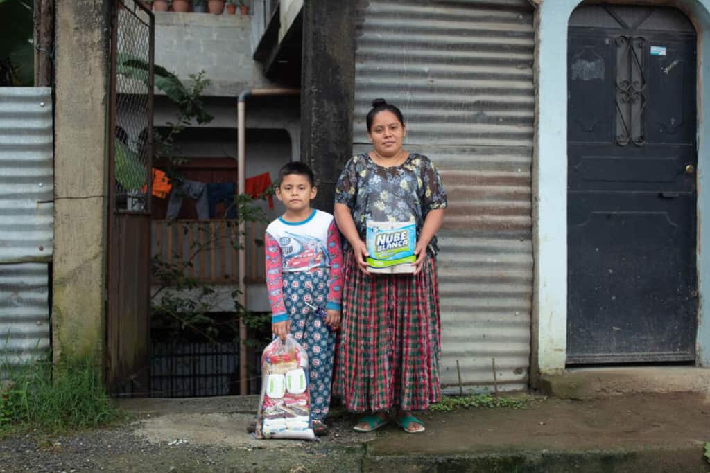 Elfego and his mother Amelia stands outside the room they are renting while they wait for the water level to lower at their house.